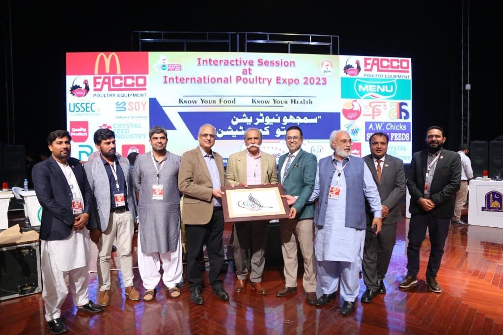 Group of poultry industry professionals at International Poultry Expo 2023 with event banner