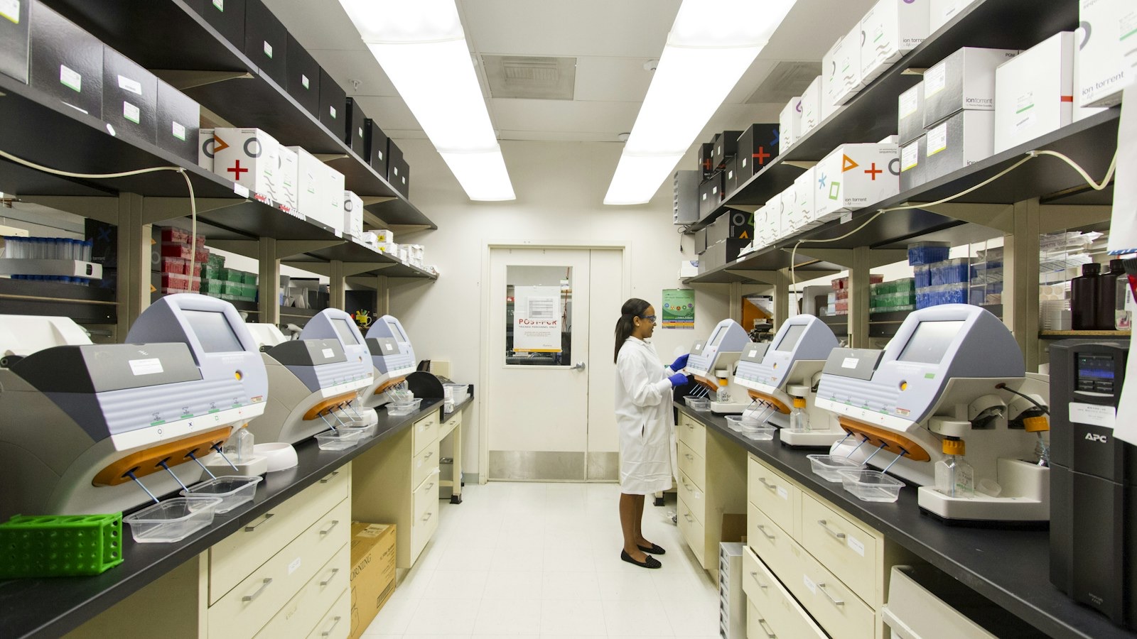 Technician working at laboratory instruments in a controlled environment